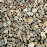 A close-up of small pebbles and gravel in a green container, with a small black handwritten label reading 'WELSH BROWN 10MM'.