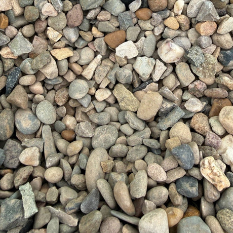 A close-up of small pebbles and gravel in a green container, with a small black handwritten label reading 'WELSH BROWN 10MM'.
