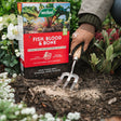 Person gardening with Westland Fish, Blood & Bone fertilizer packaging in the foreground.